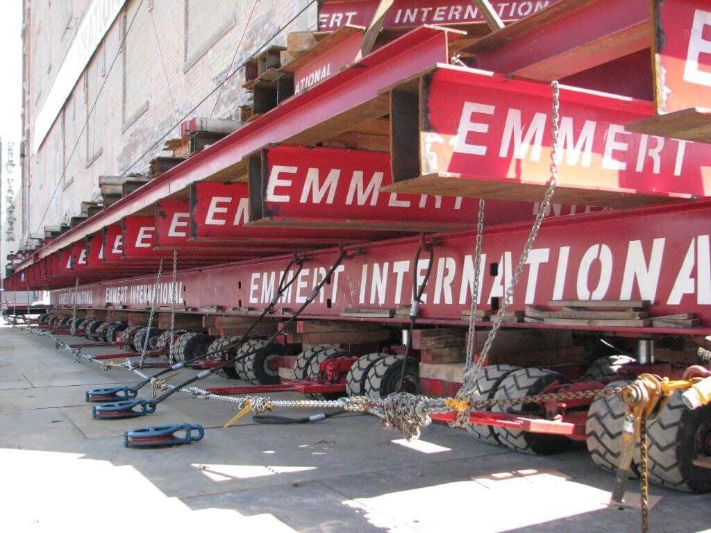 Red Emmert beams and dollies supporting a historic building during relocation